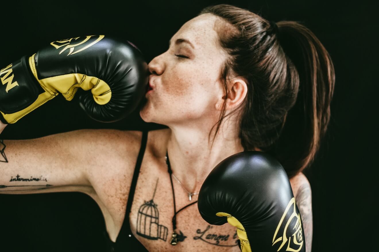 Smiling woman kissing boxing gloves