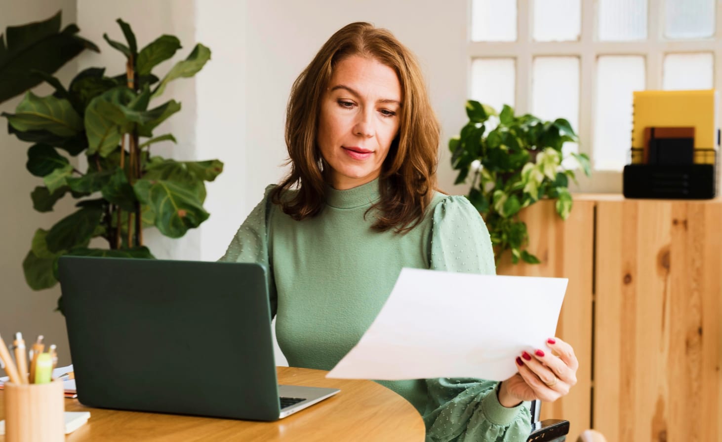 Woman sitting at a desk looking at a sheet of paper