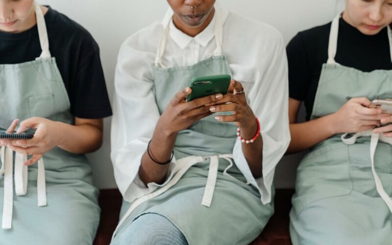 three women sitting looking at phones
