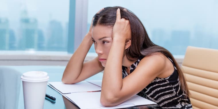 Woman at desk with head in hands
