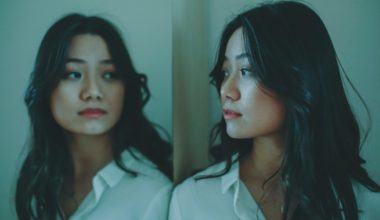 woman looking at herself in the mirror wearing a white shirt