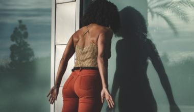 woman with head against window with arms stretched behind her