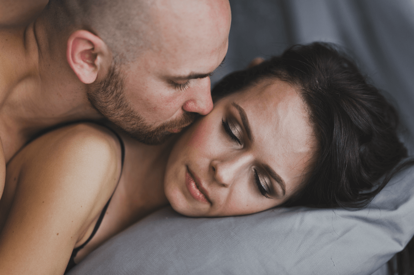 man kissing woman in bed